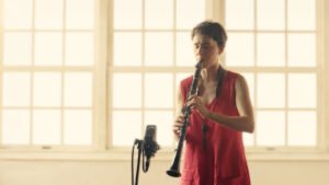 Thumbnail do vídeo: Joana Queiroz tocando clarone com luz de janela na Produção de Videoclipe Musical em Live Session – Tradução Autoral | Lampejo Filmes