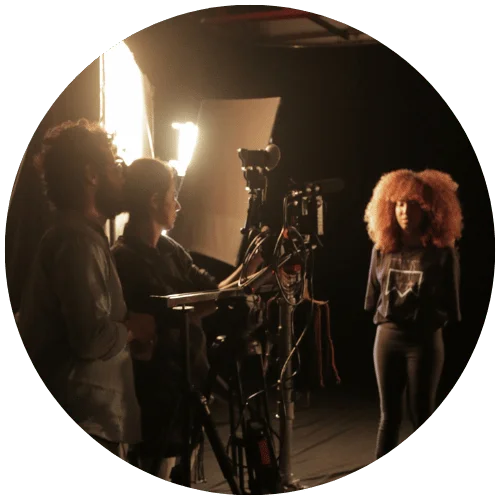 Recorte circular de Marcelo Martins Santiago e Karol Saldanha operando câmera em set profissional. Imagem associada ao Bloco de Senioridade da Lampejo Filmes, Produtora de Vídeos Corporativos no Rio de Janeiro.